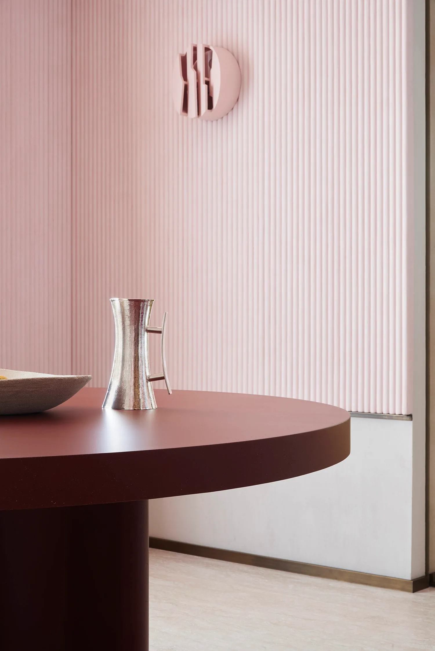 A minimalist functional zone featuring a metallic table with a bowl and a metallic jug on it.