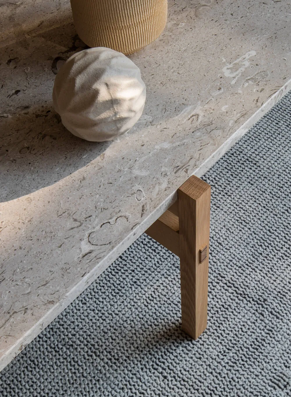 A modern, minimalist coffee table with a curved, textured surface made of concrete, accompanied by decorative objects and a t
