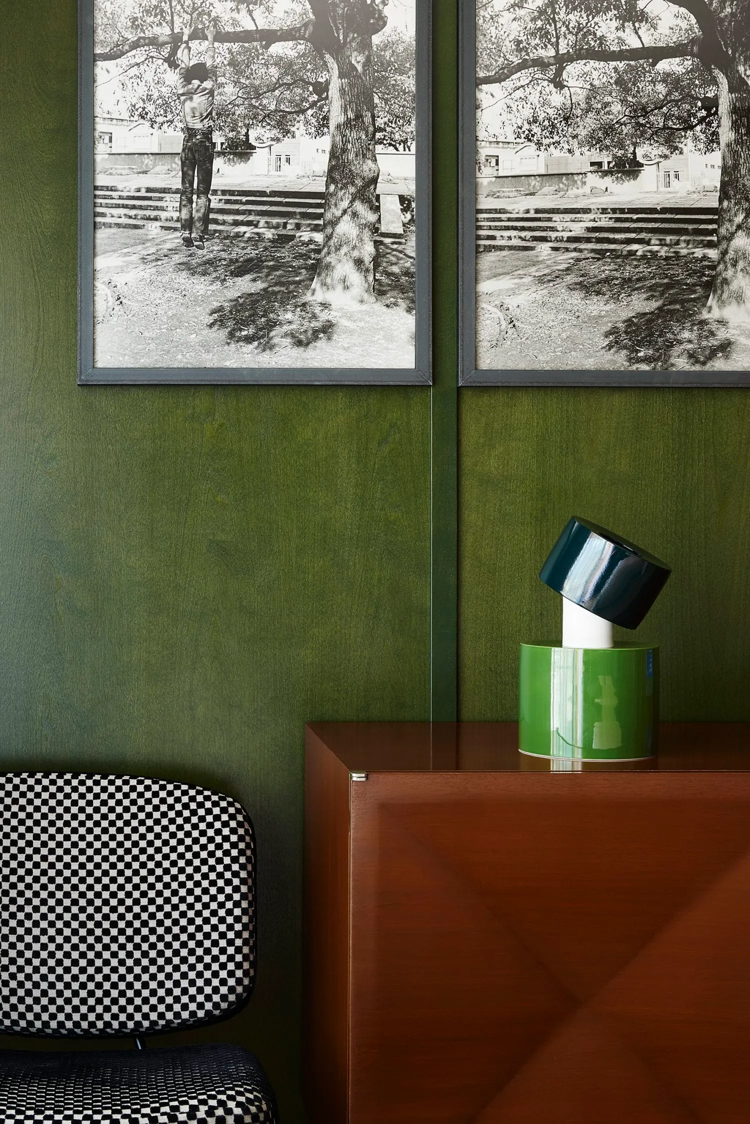 A modern interior design featuring a wooden cabinet and a black and white photograph on a green wall.