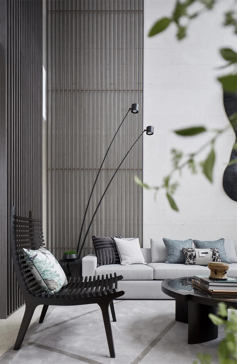 Modern minimalist living room featuring a sleek concrete wall, grey sofa, and black armchair