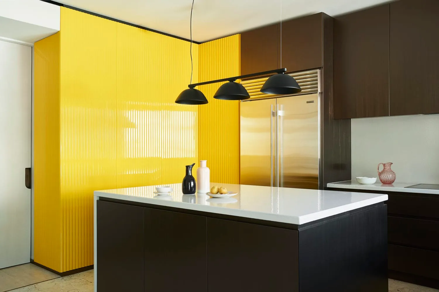 Modern kitchen featuring a yellow backsplash and stainless steel appliances, surrounded by brown cabinets.