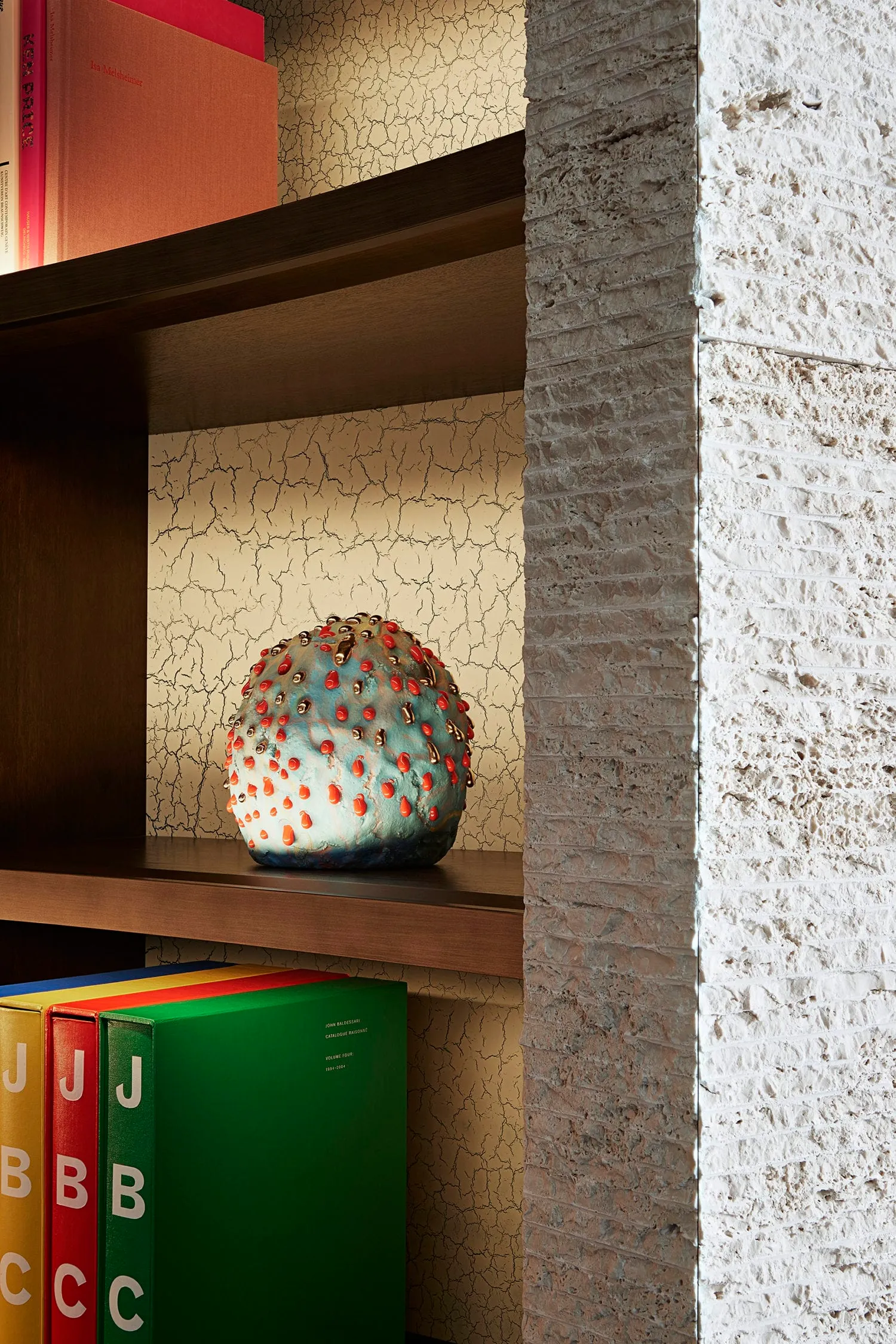 A ceramic object with red and gold accents sits on a wooden shelf in an urban industrial interior design setting.
