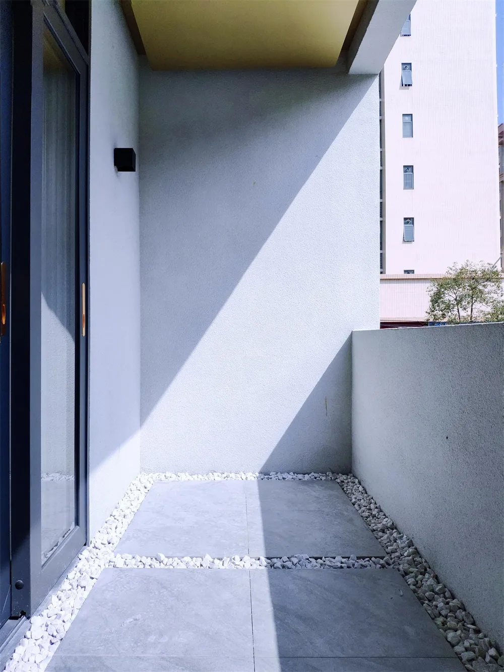 Clean, minimalist outdoor space with concrete flooring and white pebbles.