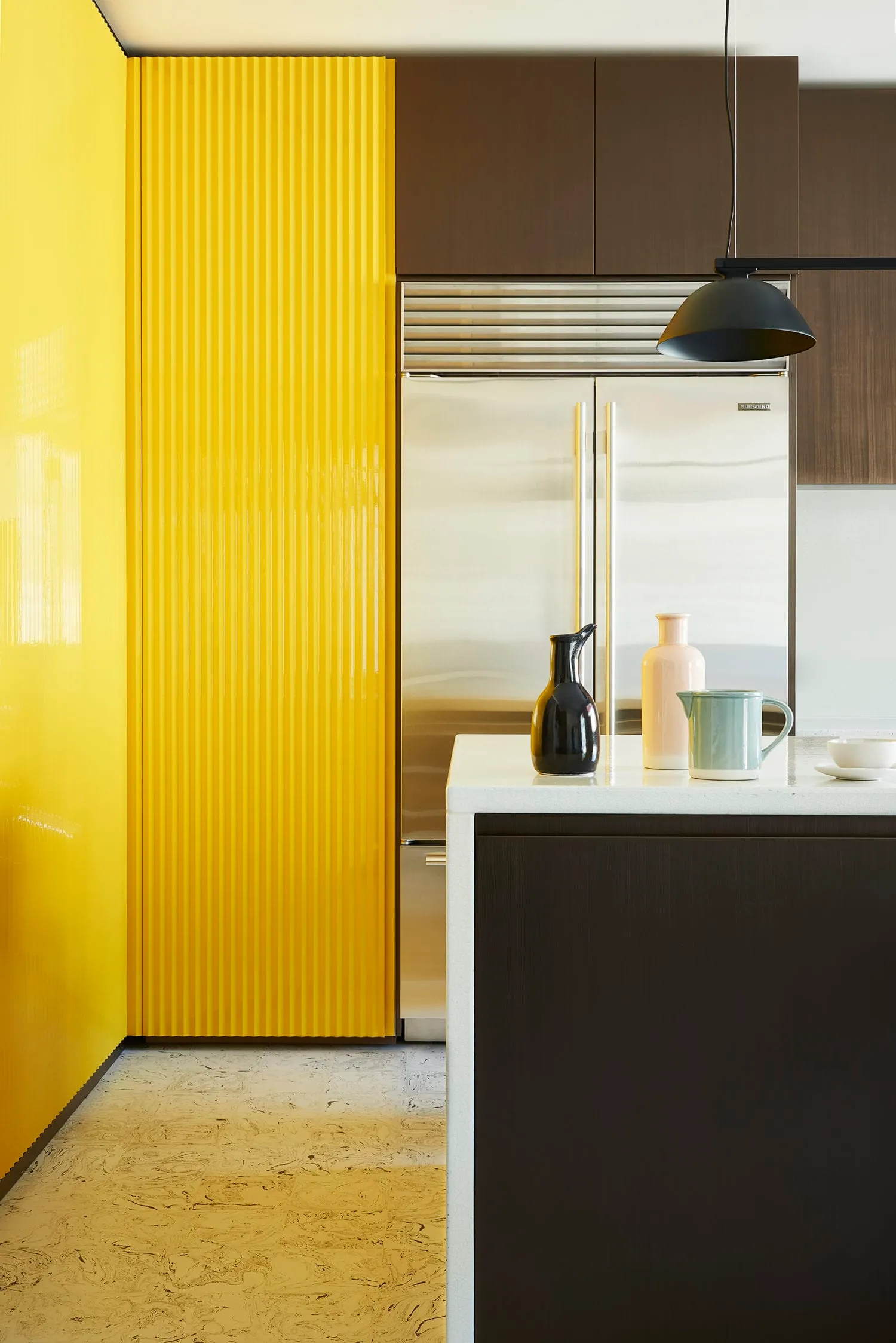Modern kitchen featuring a yellow metal cabinet, polished wood accents, and ceramic elements.