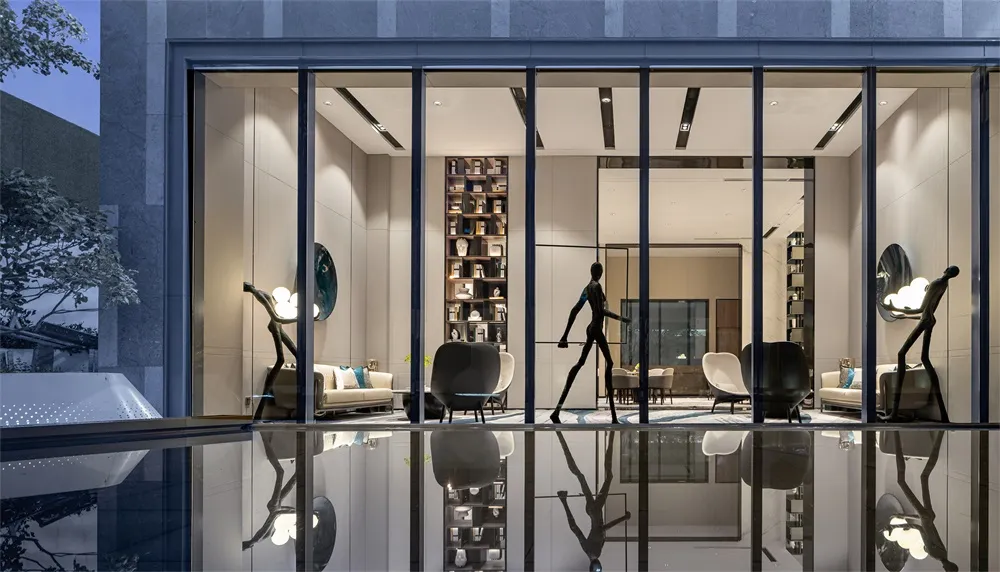 Modern lobby interior with glass walls and furniture, reflecting in the water.