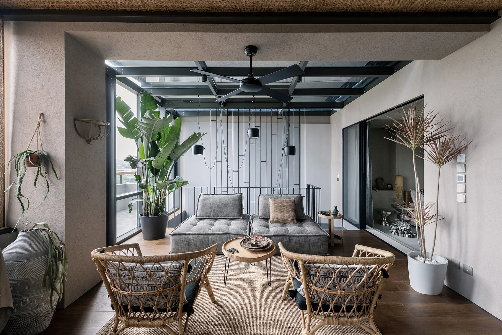 Modern living room with minimalist design, featuring grey upholstered seating, rattan chairs, and wool rug