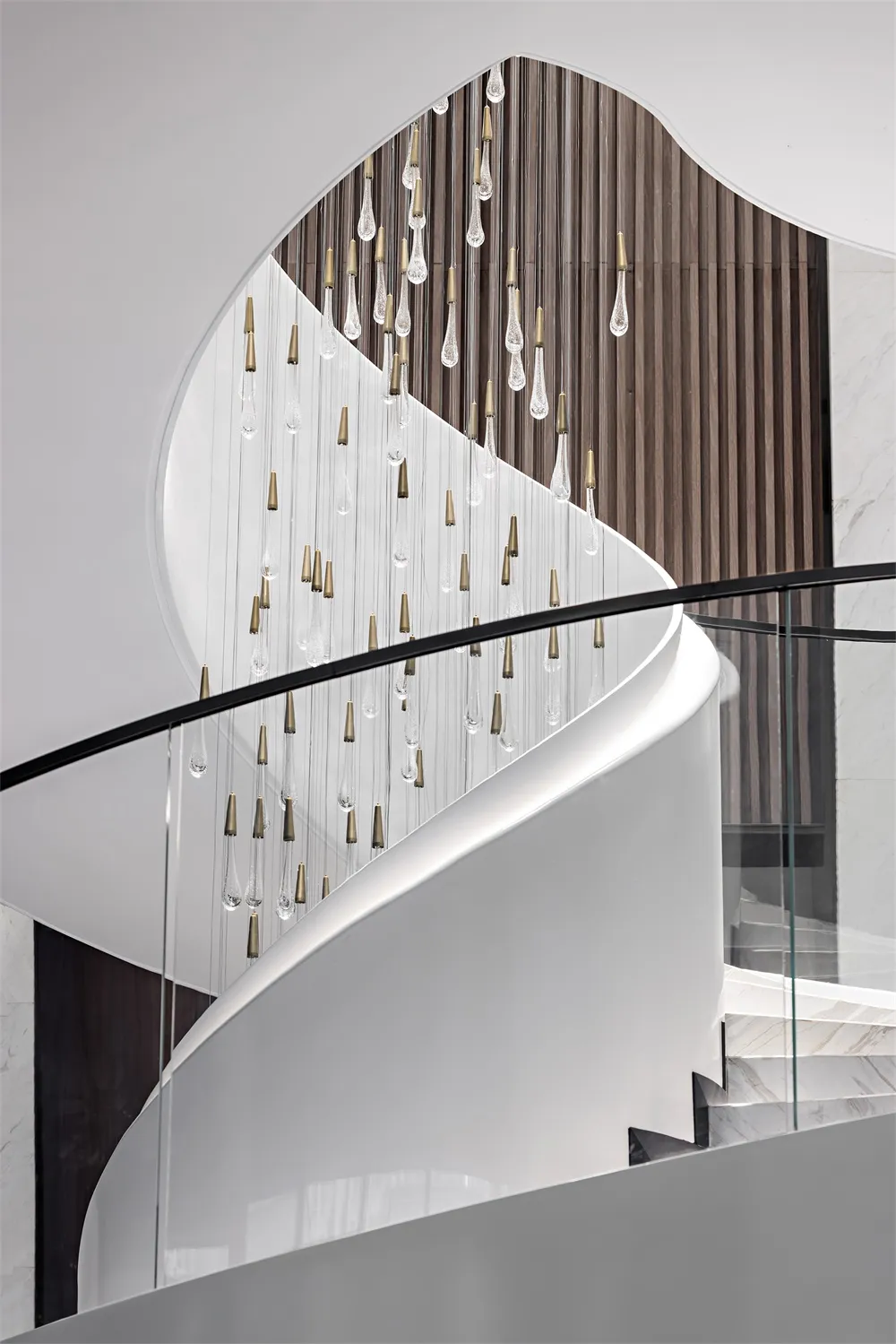 A modern staircase features glass, bronze, and metal details.