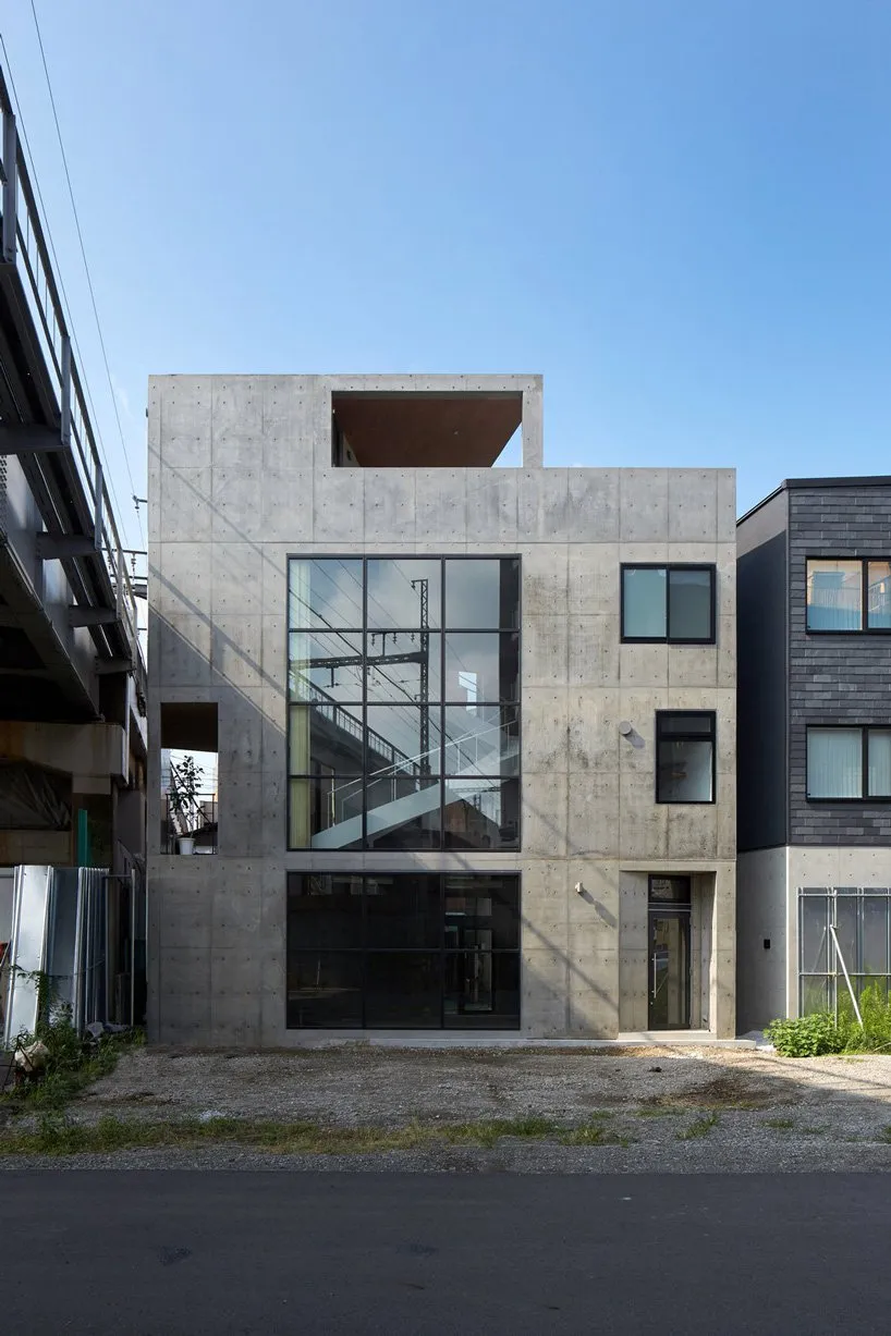 Modern concrete house with large windows and concrete exterior.