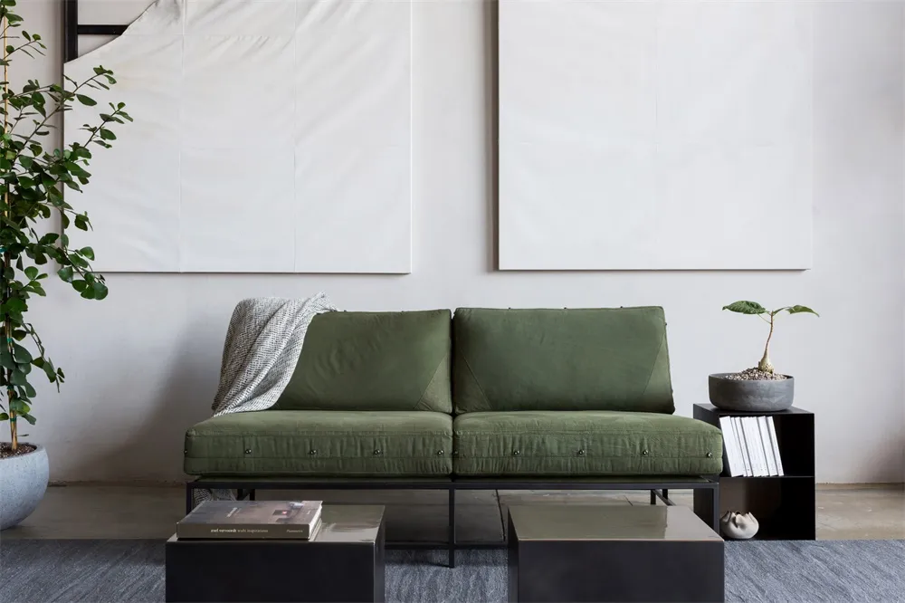 A modern living room featuring a green upholstered sofa with minimalist design elements, black metal coffee tables, and a whi