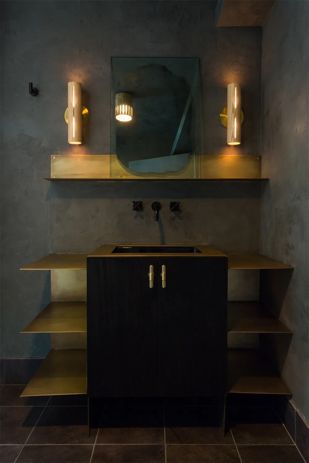 A modern minimalist bathroom featuring a brass cabinet with an integrated sink, accompanied by minimalist sconces and a textu
