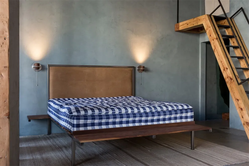 A minimalist bedroom with a wooden bed frame, checkered bedspread, and a leather headboard.