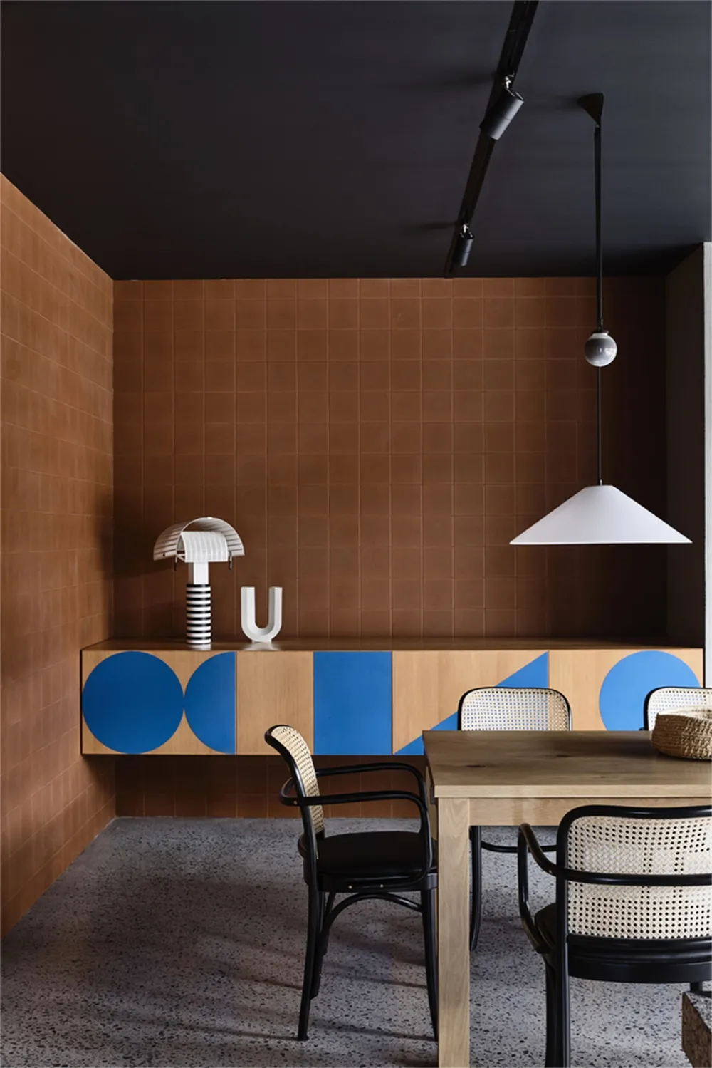 A modern restaurant interior featuring wooden tables and geometric-patterned walls.