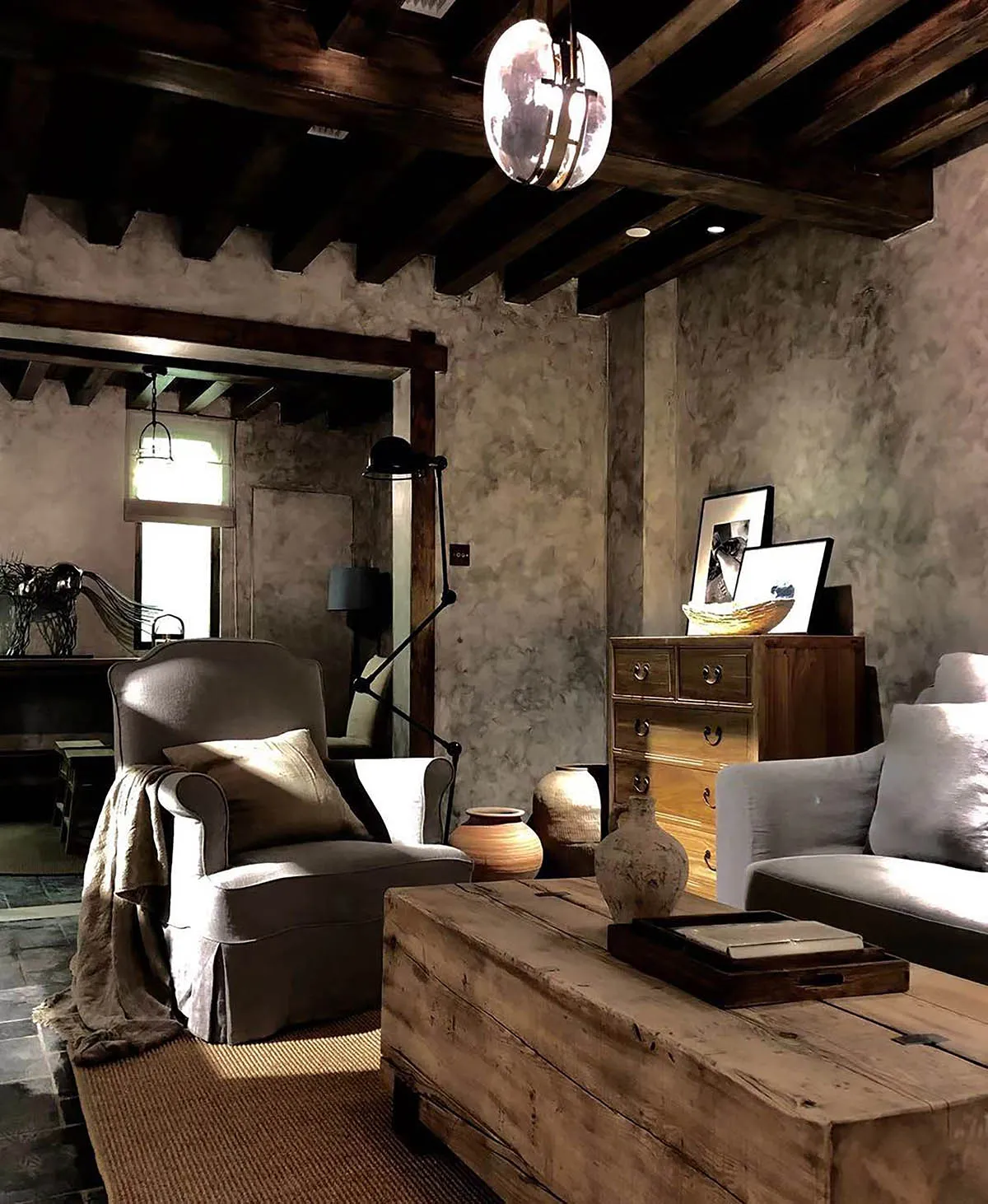 A cozy industrial-style living room featuring rustic wooden furniture and semi-transparent ceiling beams.