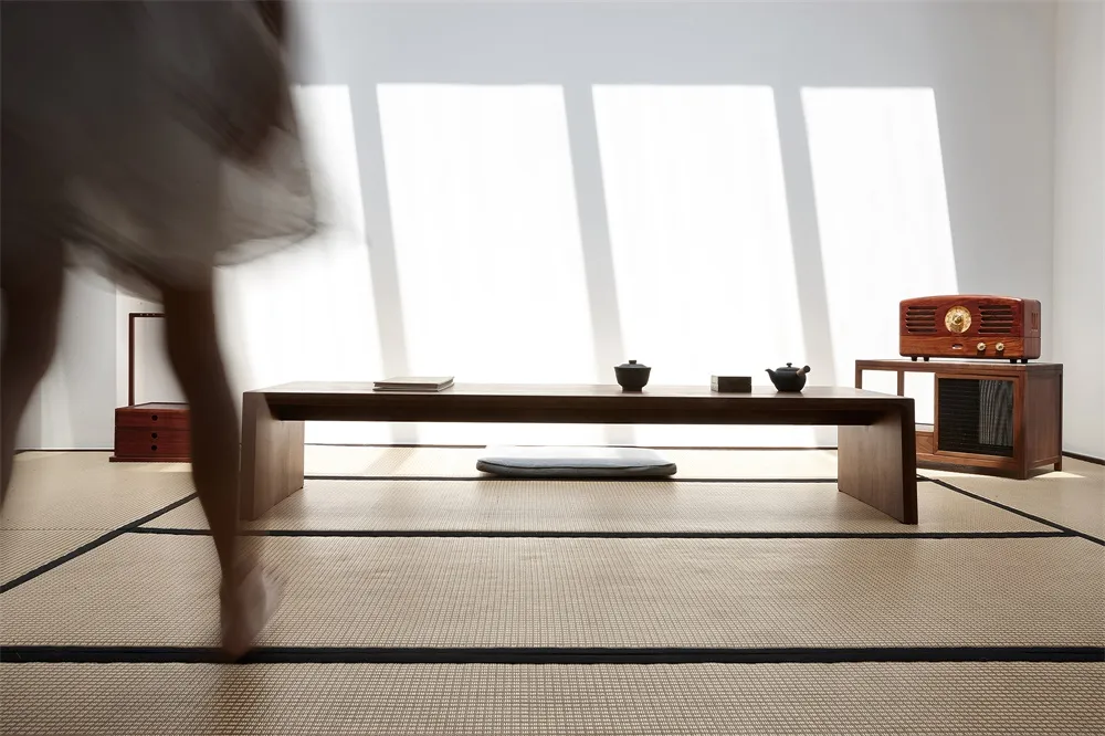 A modern living room features wood furniture and a concrete floor with large windows allowing natural light to flood the spac