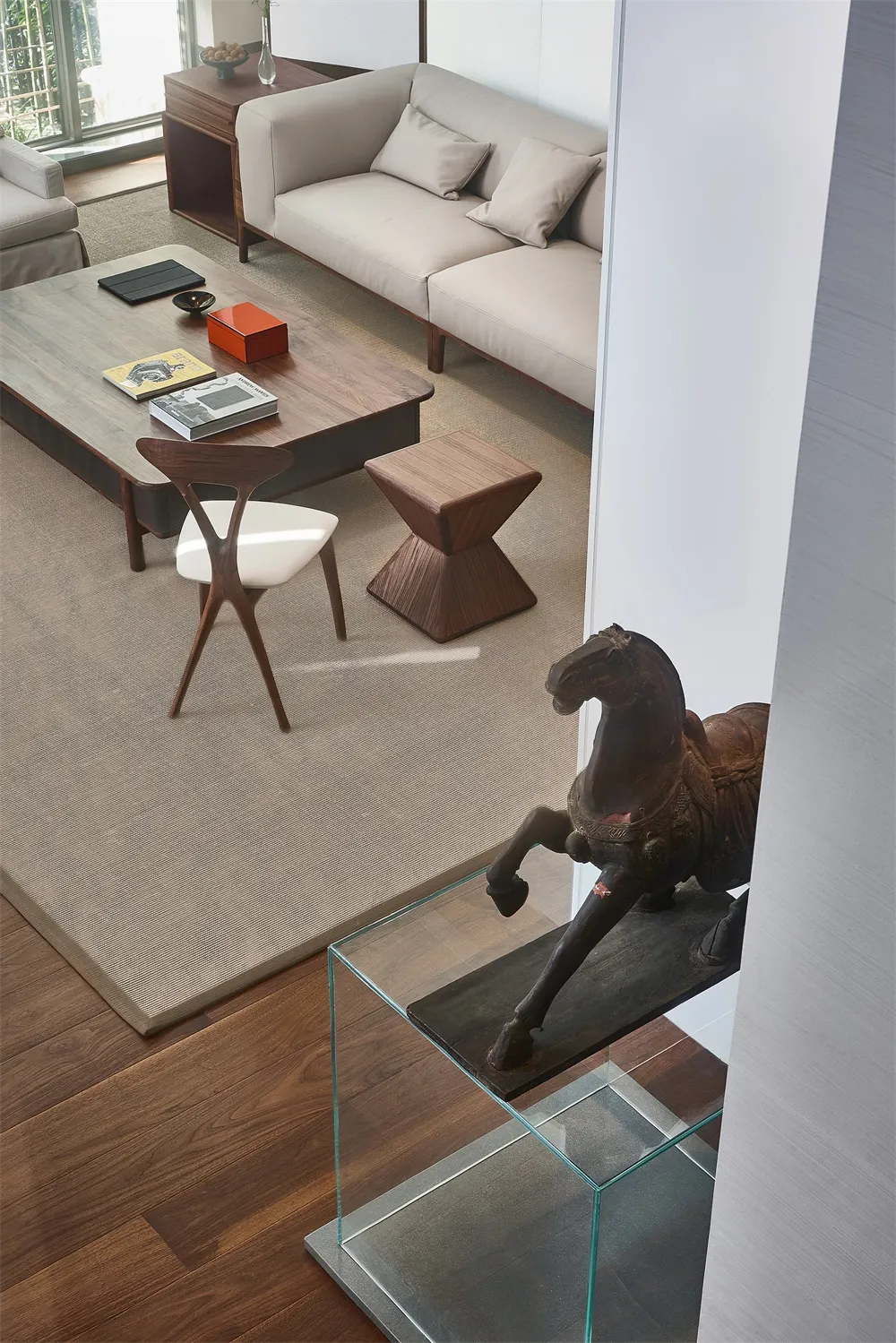 A modern living room featuring a wooden table, fabric sofa, and glass sculpture.