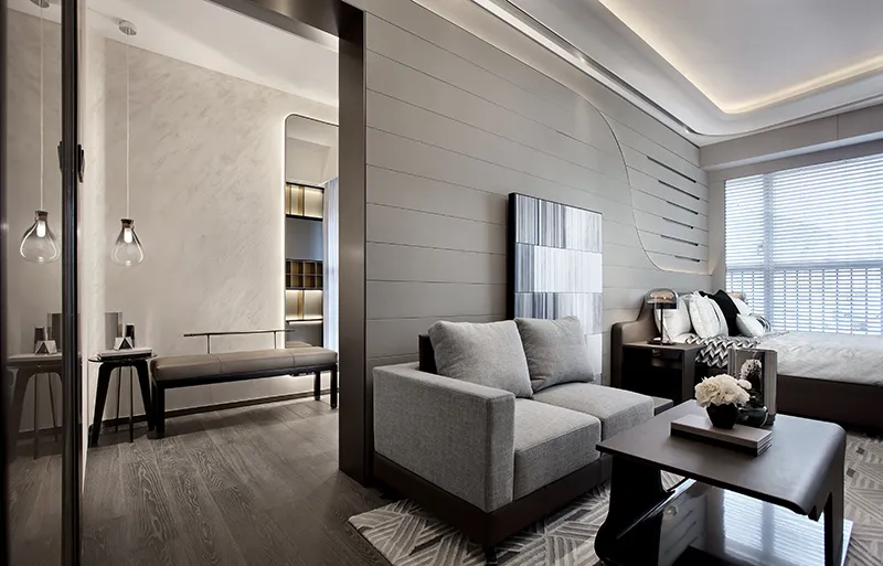 Modern minimalist living room with a grey fabric sofa, wooden flooring, and metal accents.