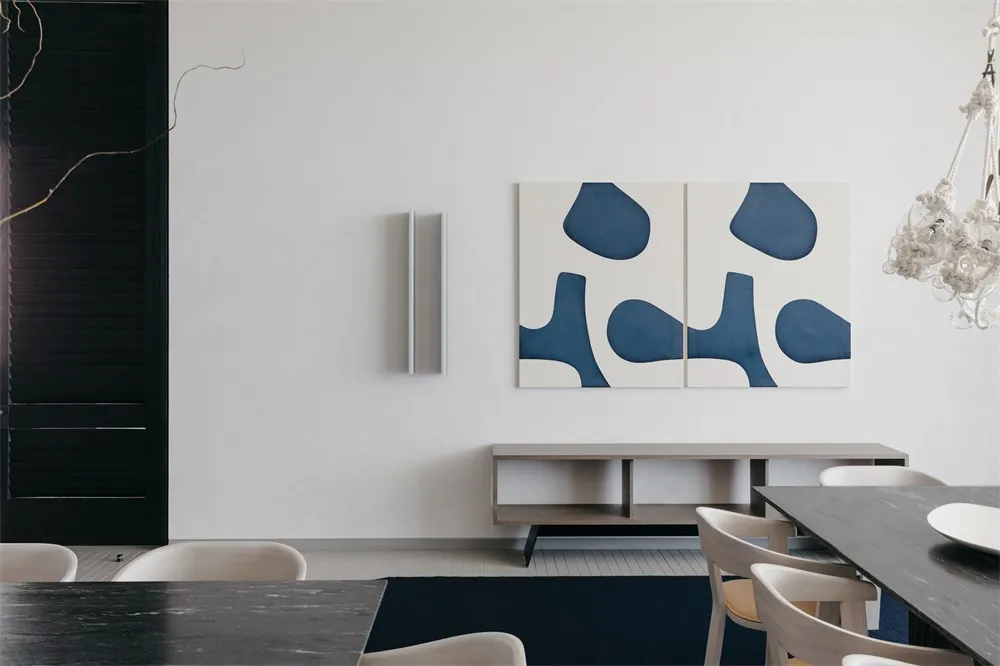 Modern living room with polished concrete floor, white walls, and abstract blue art on the wall.