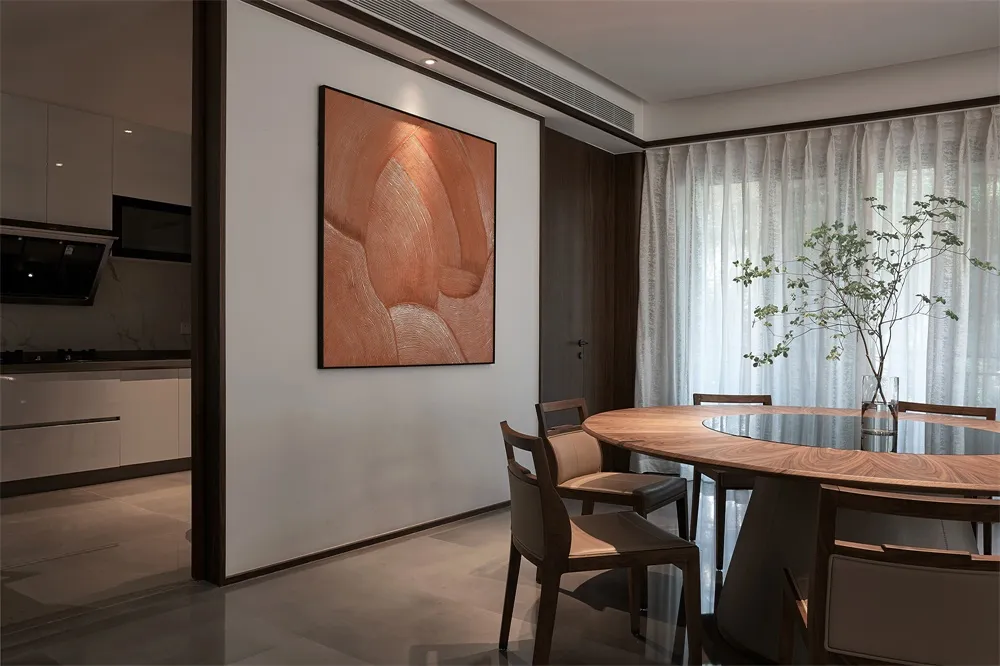 A modern residential dining room with a wooden table and chairs, white curtains, and brown art on the wall.