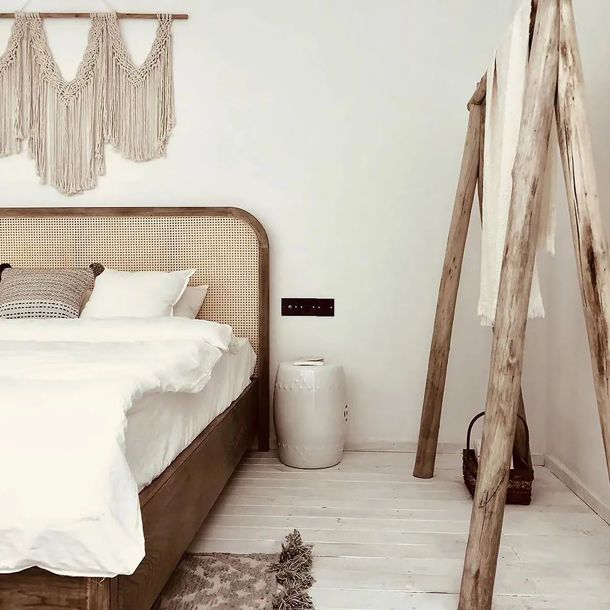 Minimalist bedroom with wooden cane bedframe, white bedding, and modern decor.