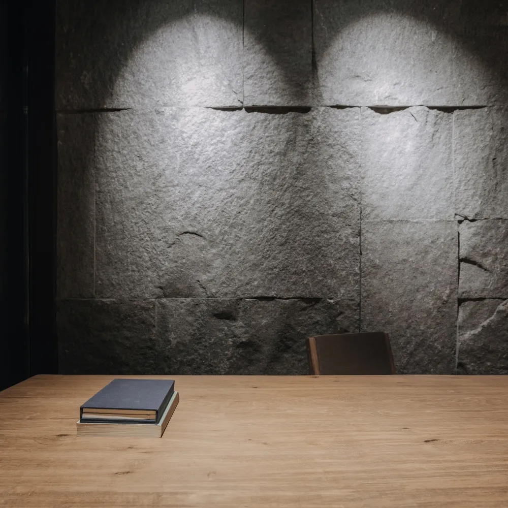 Minimalist workspace with industrial design, featuring a wooden table and stone wall