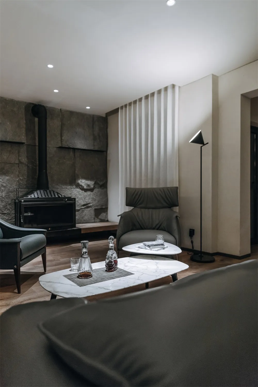 Modern minimalist living room featuring marble coffee tables and a leather armchair, providing a comfortable and sophisticate