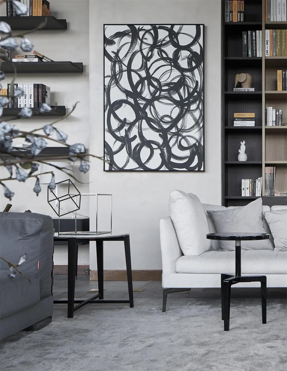 一間現代客廳，擺放中性色調家具，牆上掛著黑白抽象畫作。