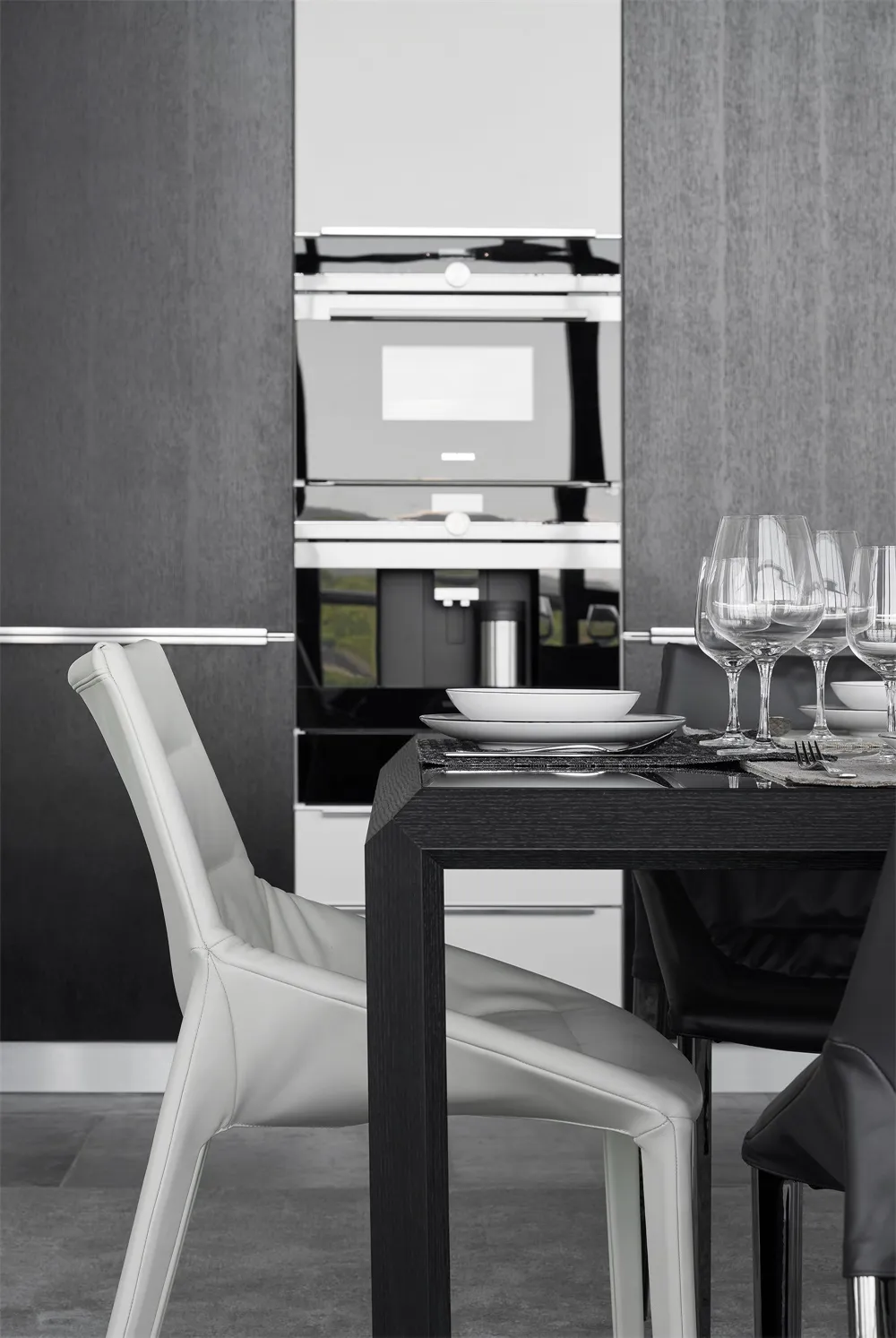 Modern kitchen with white leather chairs and black dining table.