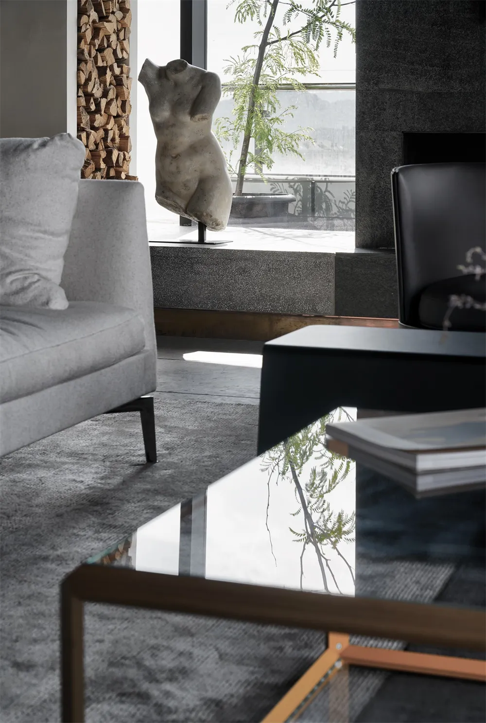 A modern minimalist living room featuring a glass coffee table and a sleek black leather chair.