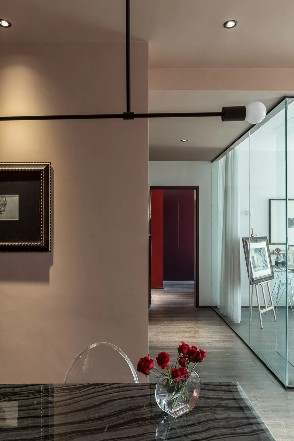 Modern living room featuring a glass dining table with red roses in a vase, sleek lighting, and minimalist decor.