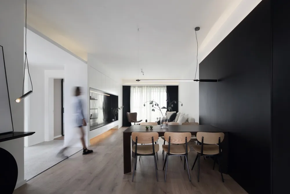 A modern minimalist living room with black walls, wooden furniture, and glass elements.
