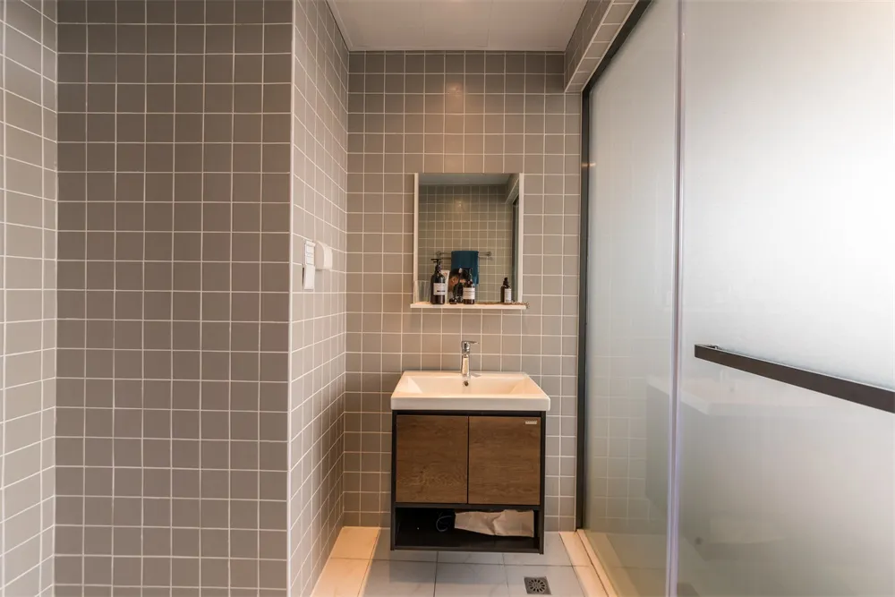 Modern bathroom with gray tile walls, a sink, and a mirror.