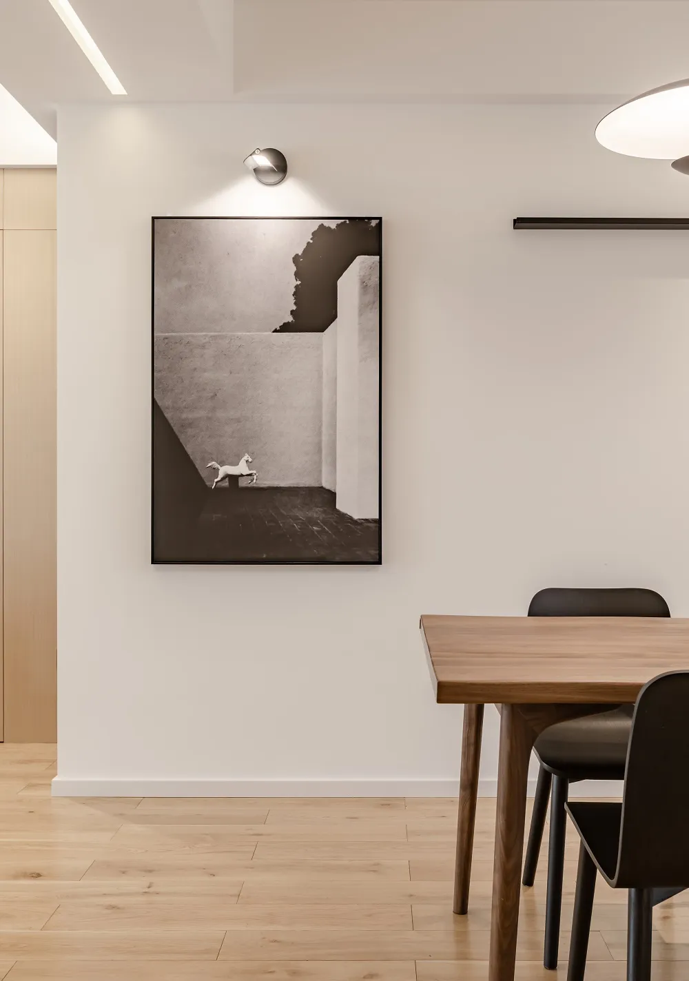 A modern minimalist interior design with wooden furniture and black accents, featuring a black and white photograph of a hors