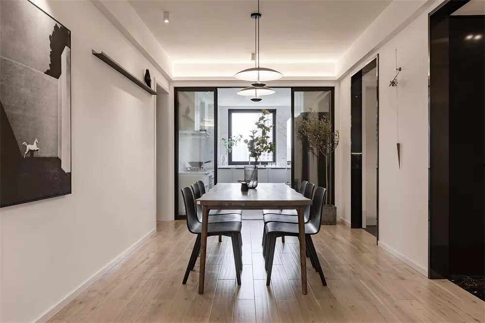 A minimalist dining room with a wooden table and black chairs, featuring modern decor and a sleek design.
