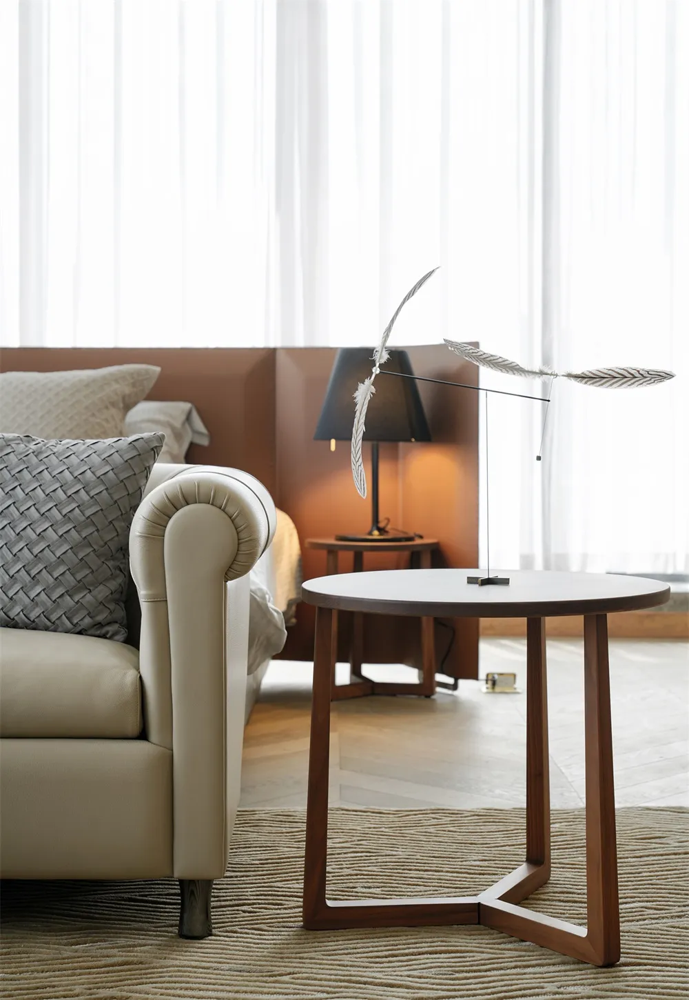 A minimalist bedroom featuring a leather sofa, fabric pillows, and a wooden side table.