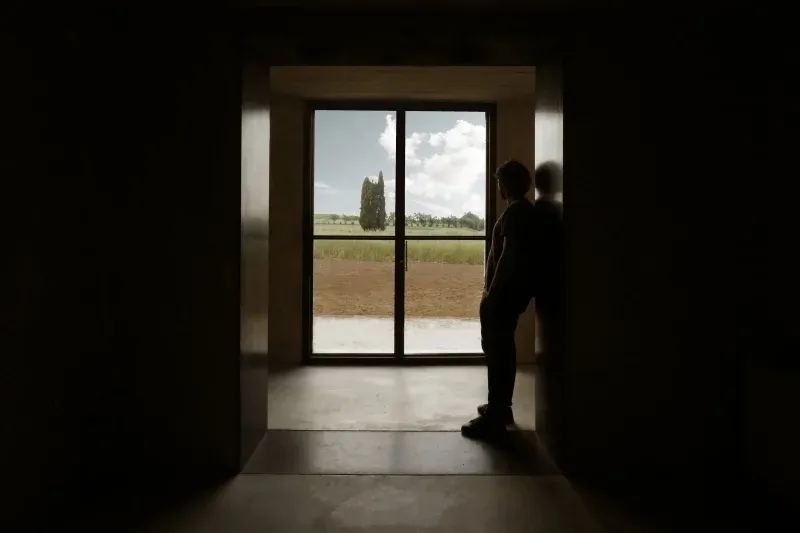 A minimalist window with a glass pane, framed by a dark interior space, overlooking a serene outdoor landscape.