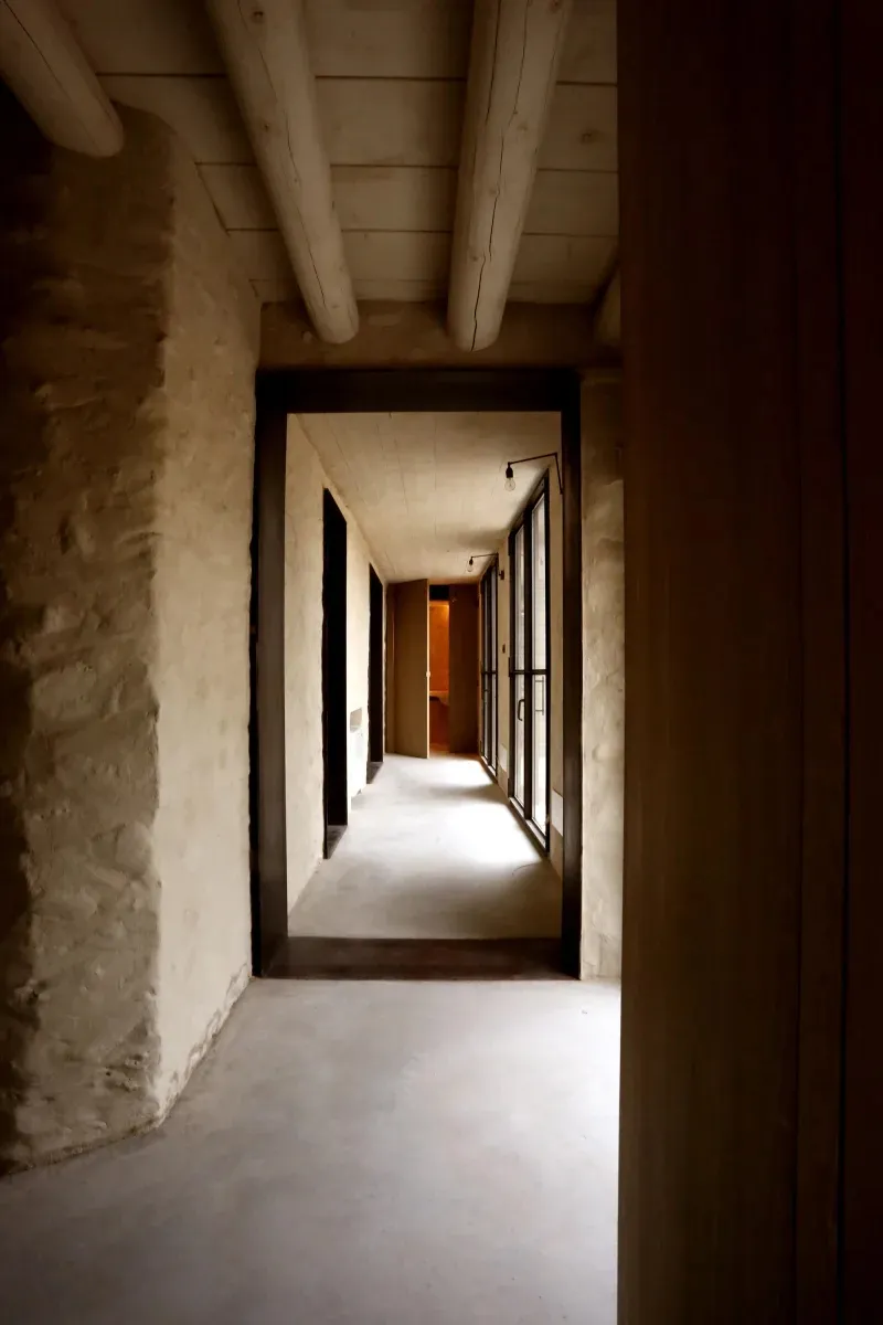 Modern concrete corridor with exposed ceiling beams and wooden panels.