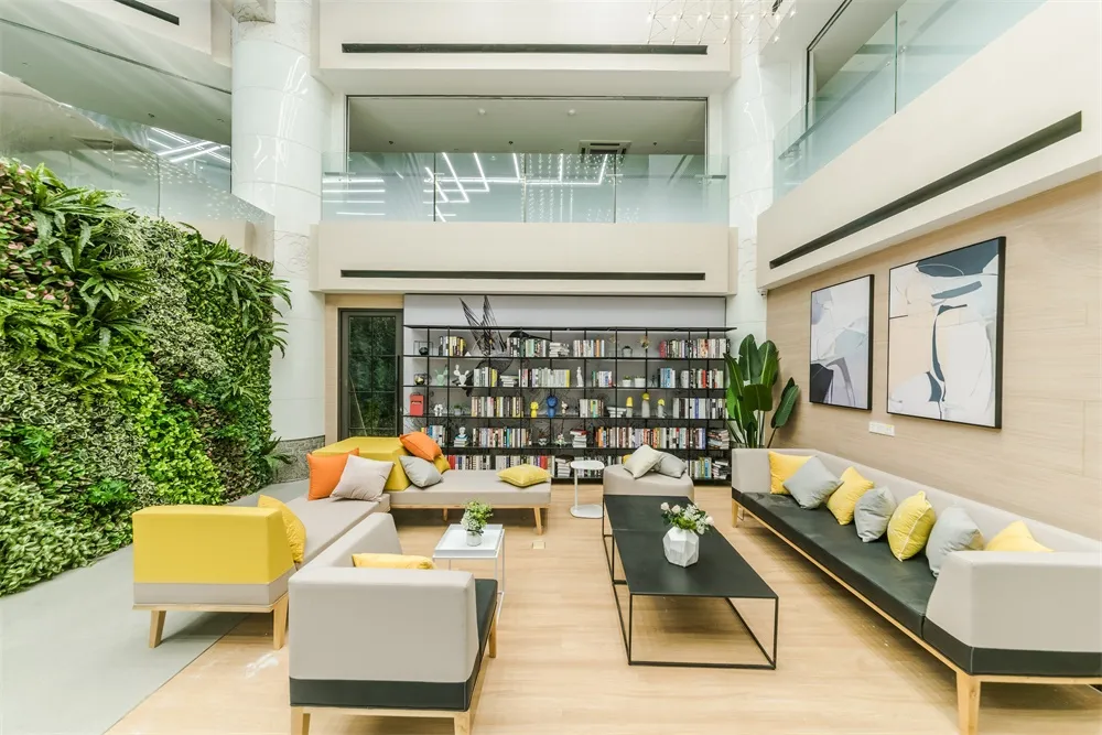 A modern lounge space featuring a variety of materials including upholstered furniture, a green living wall, and a large book