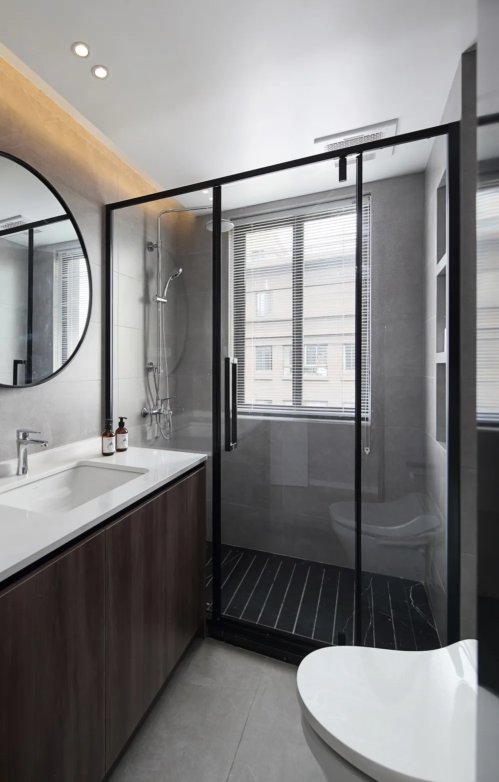 Modern bathroom featuring a glass-walled shower enclosure with dark wood cabinets and white porcelain floor tiles.