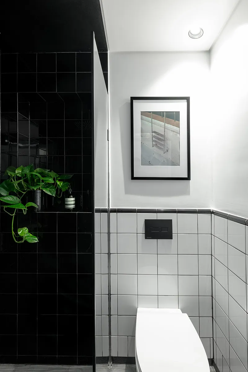 Minimalist black and white bathroom with a white toilet and black tiled walls.