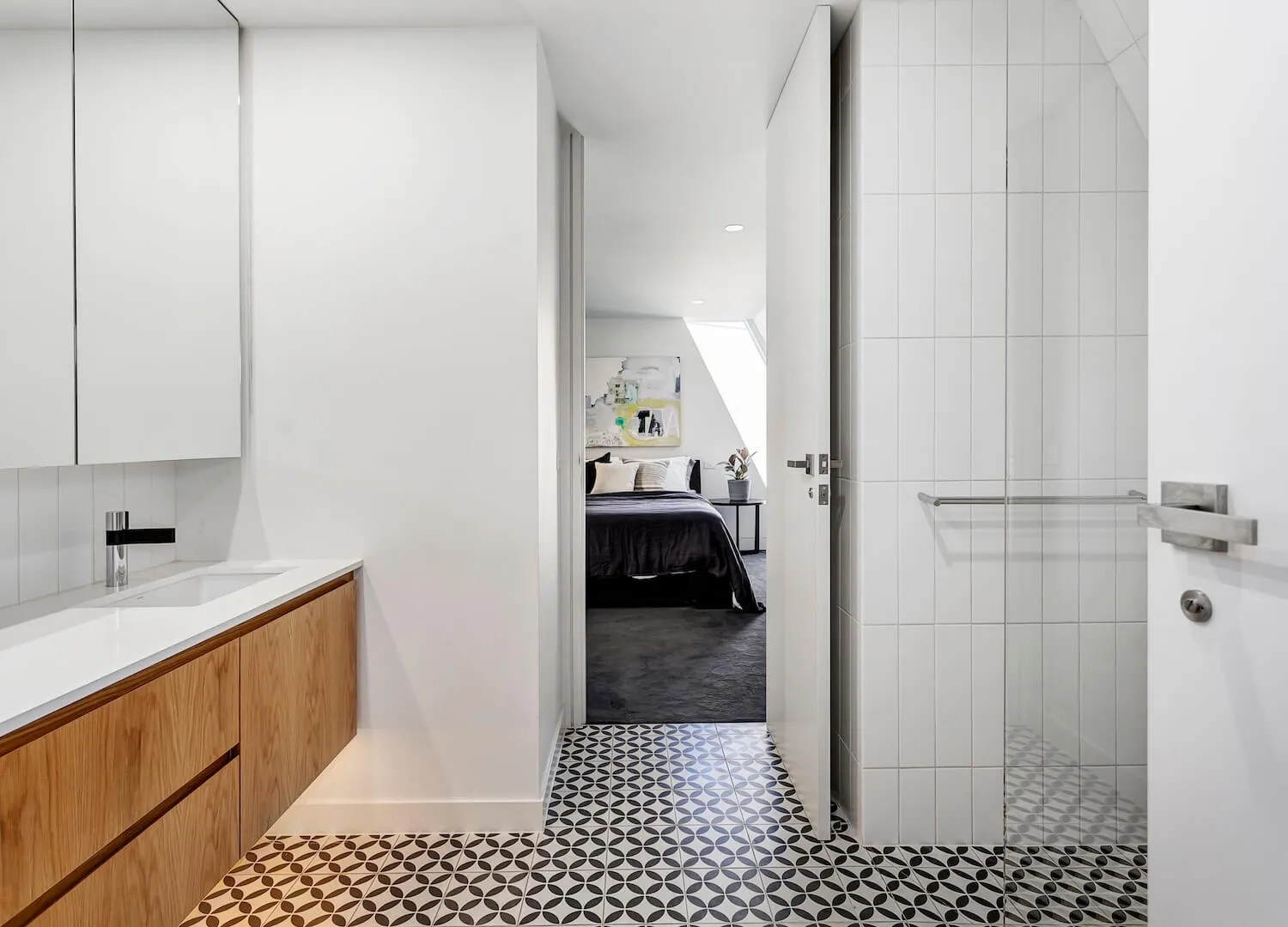 A modern white bathroom with a patterned ceramic tile floor, wooden cabinets, and a bathroom sink.