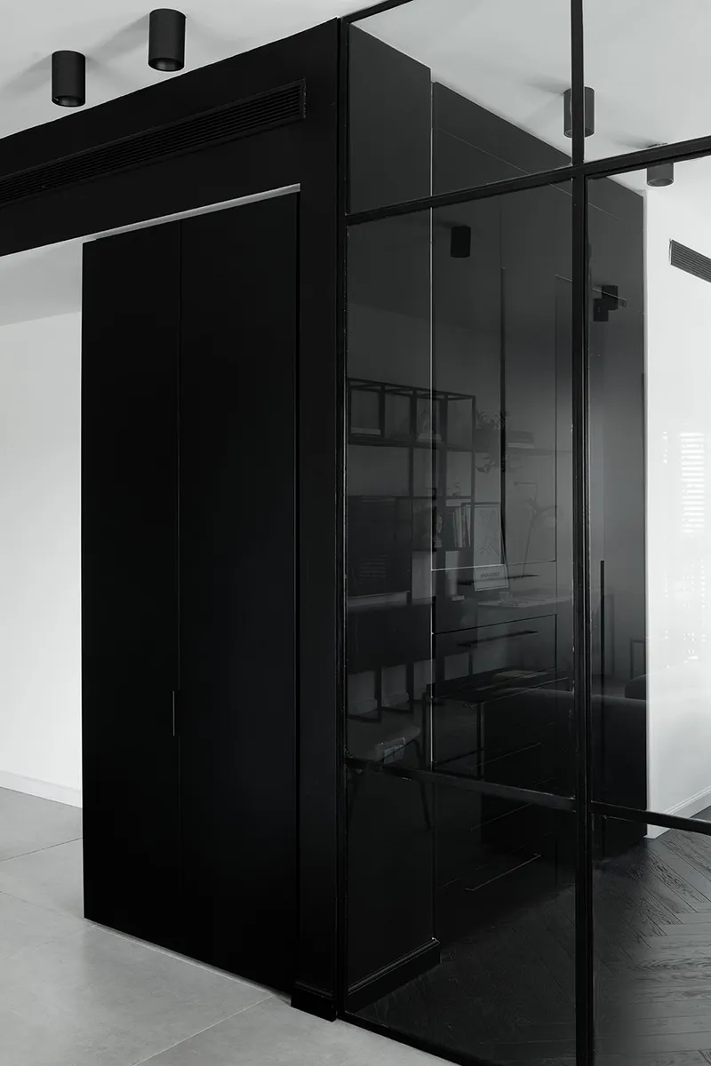 Modern black interior design featuring a glass wall and minimalist furnishings.
