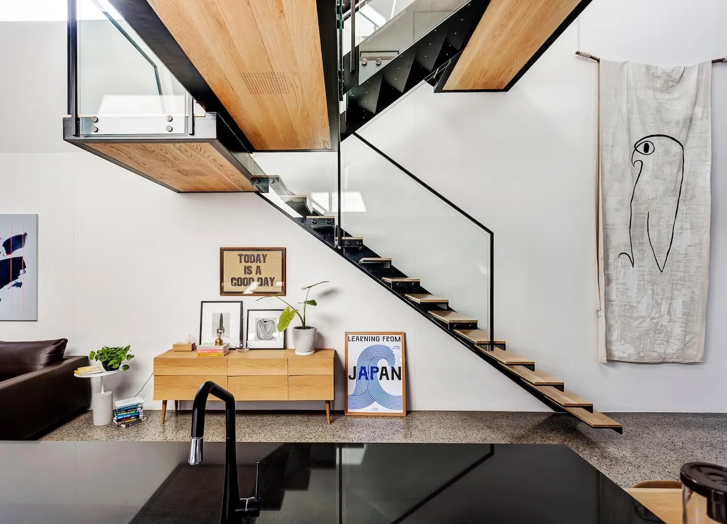 A modern living room featuring a floating staircase made of wood.