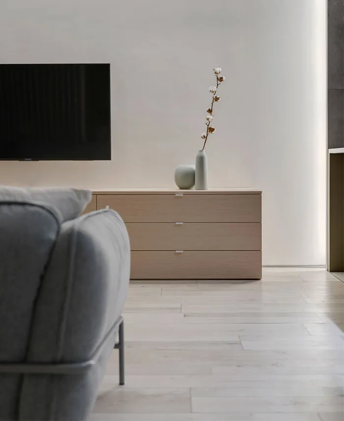 Modern living room with wooden furniture and grey sofa.