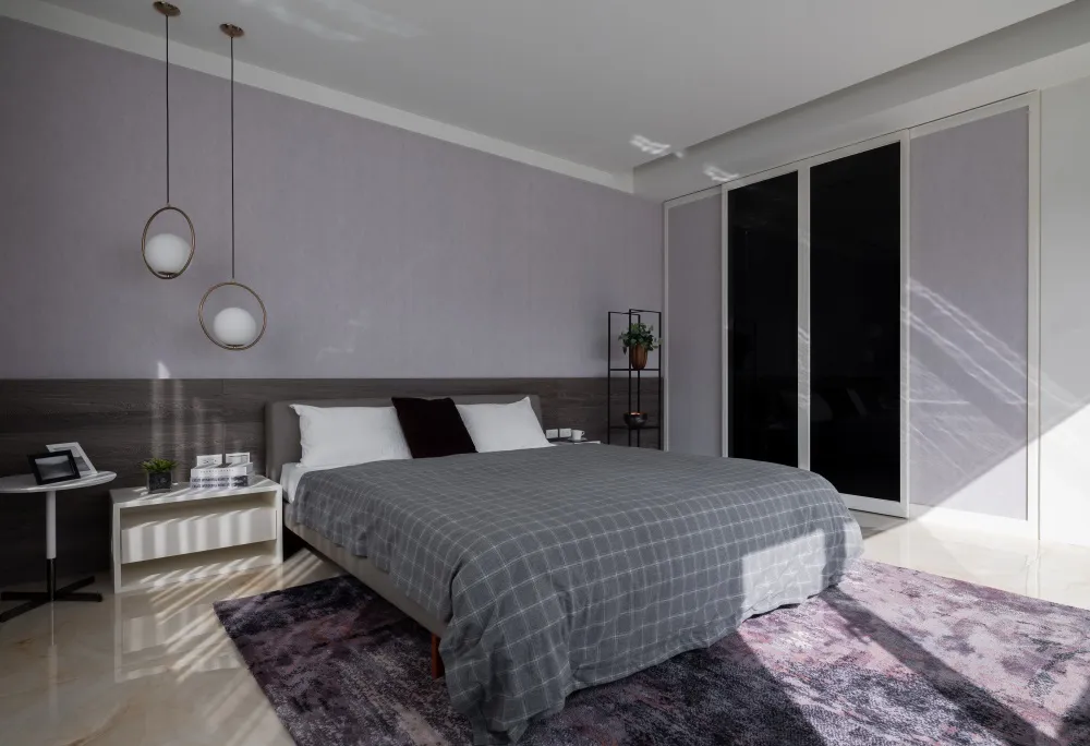 Minimalist bedroom, featuring a gray textile bedspread, modern lighting, and a wooden headboard, with a carpet, a potted plan
