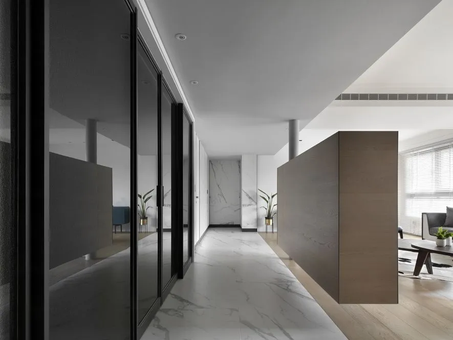 Modern, minimalist corridor featuring marble flooring and glass doors.