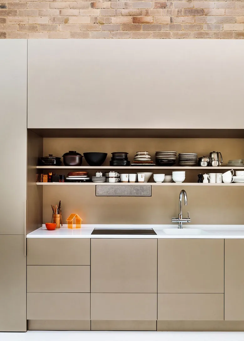 A minimalist kitchen with concrete countertops and shelves displaying various kitchenware.