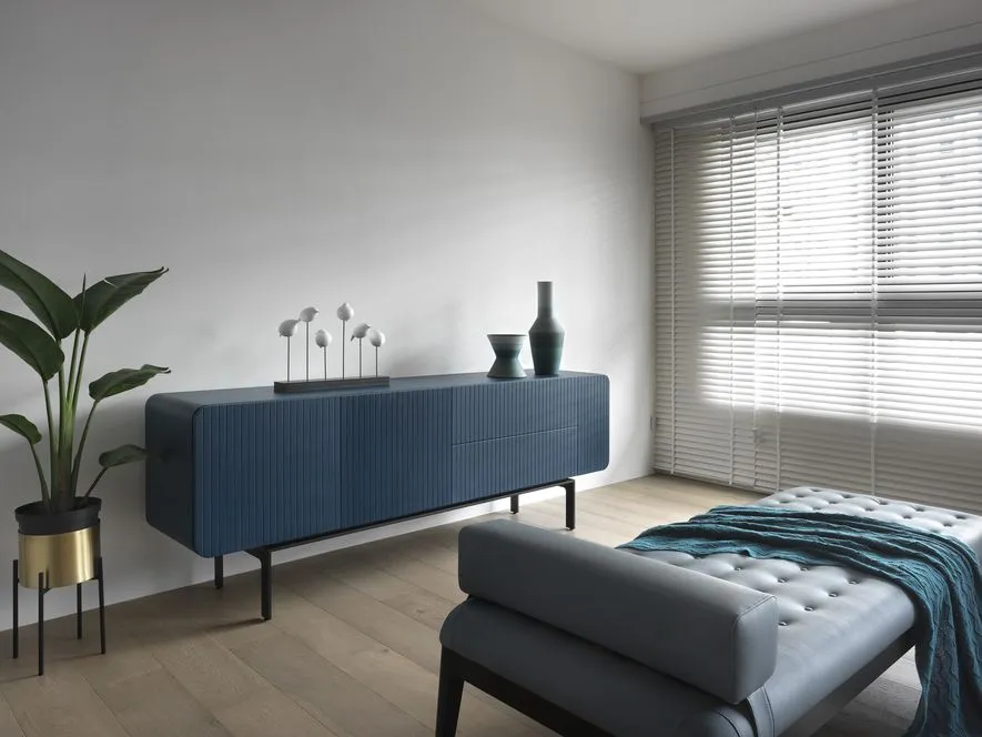 Modern minimalist living room with metallic accents, wooden flooring, and fabric seating.