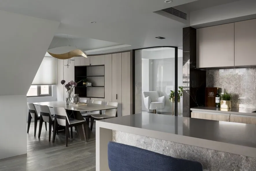 A modern residential kitchen with concrete countertops, stone backsplash, and glass elements.