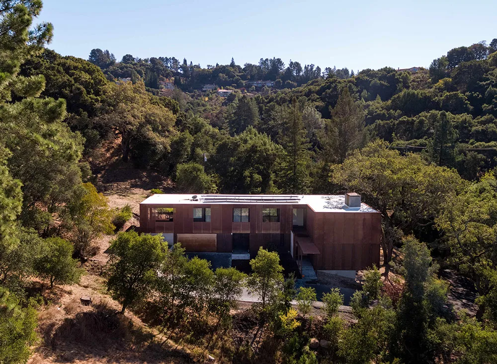 A modern residential house with wood exterior surrounded by trees.