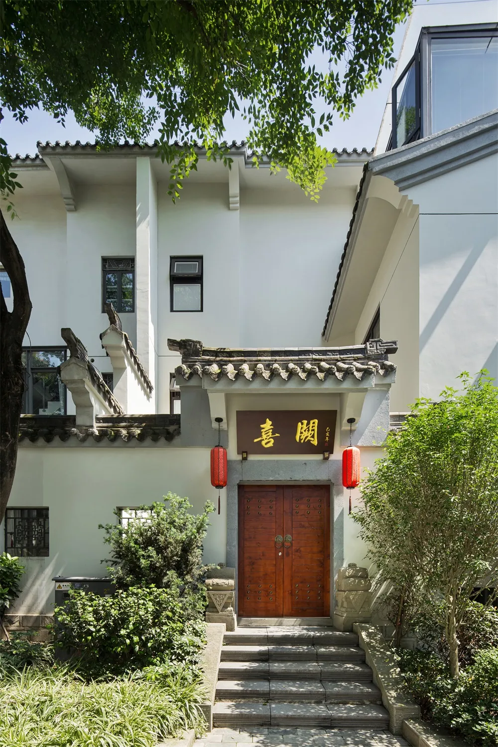 A traditional white residential entry with wooden doors and red lanterns.